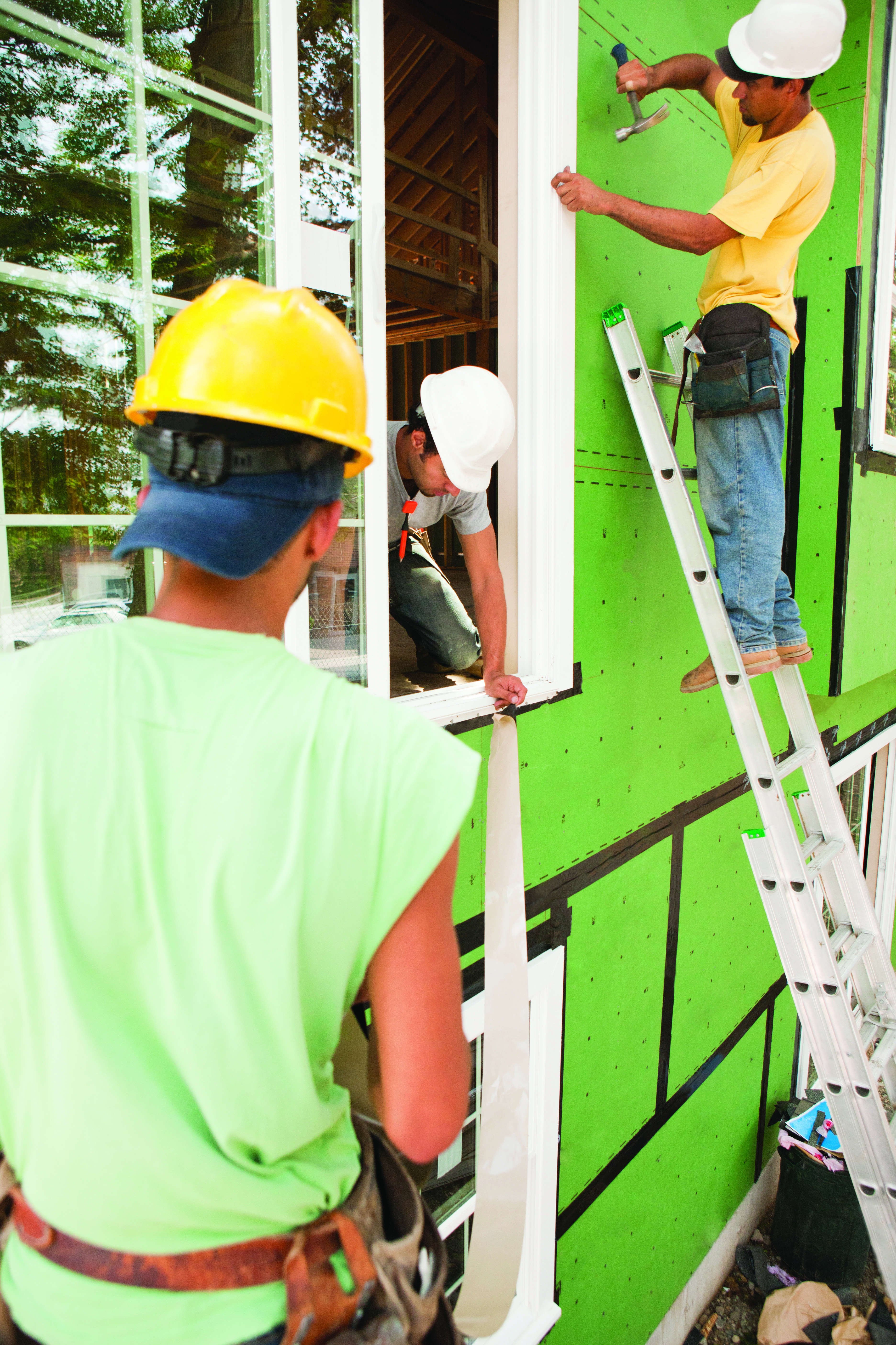 Carpenters nailing and installing flashing around window frame