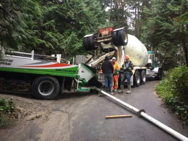 Four truckloads of concrete squeezed down a narrow road to unload at the top of the site. Note the pipe through which the concrete flows down the hill.